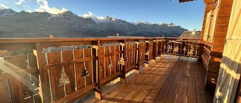 Una terraza de madera con vista a montañas nevadas.