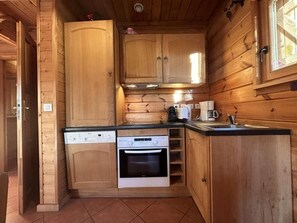 Una cocina compacta con armarios de madera, lavavajillas, horno y cafetera.
