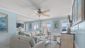 A living room with a ceiling fan, a sofa, a coffee table, and a cabinet. - Oceanview at A Place at the Beach 3 - Unit 3E (Myrtle Beach)