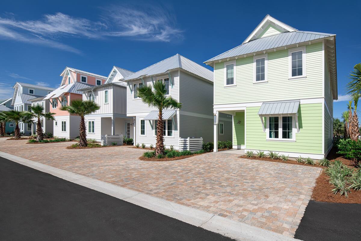 Una hilera de casas coloridas con un camino pavimentado y palmeras.