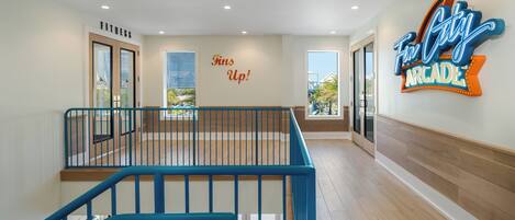 A spacious indoor area with a blue railing, a sign reading 'Fins Up!', and a neon sign for 'Fun City Arcade'.