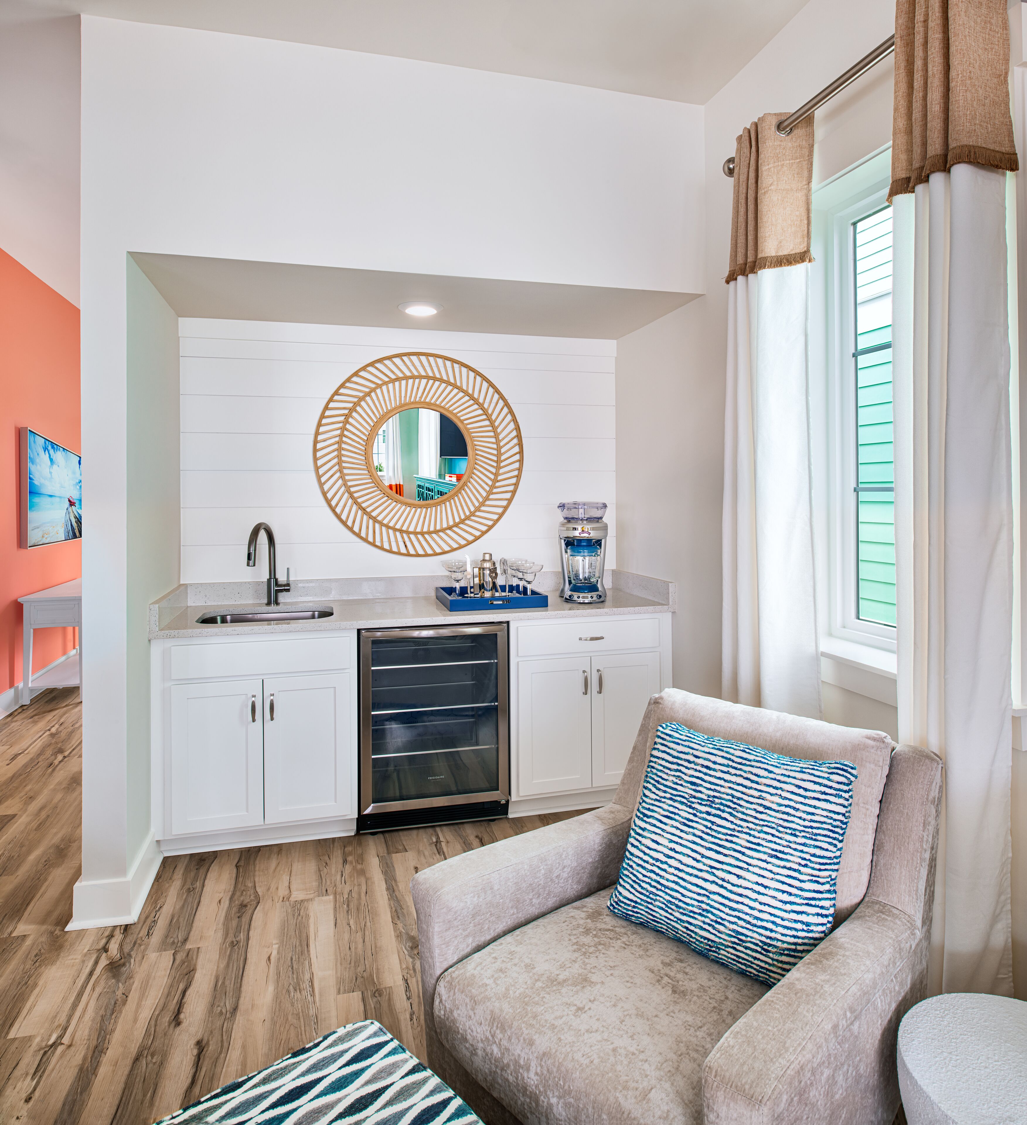 A modern kitchen with white cabinets, a built-in oven, and a round mirror above the sink.