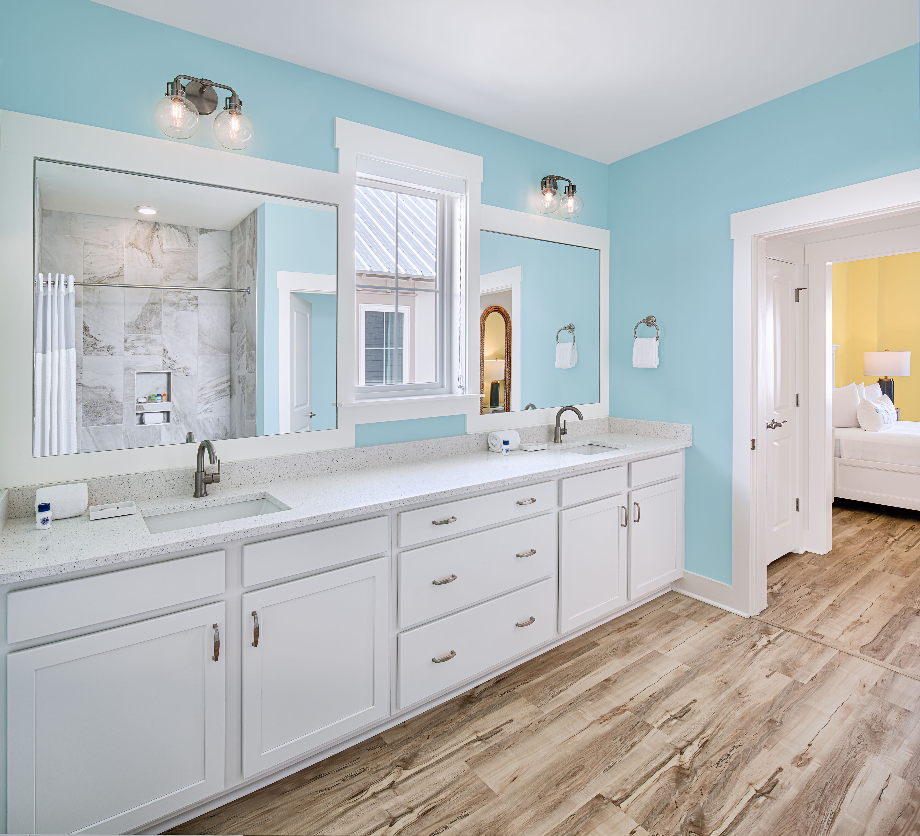 Un baño moderno con un espejo grande, dos lavamanos y un mueble de tocador con cajones.