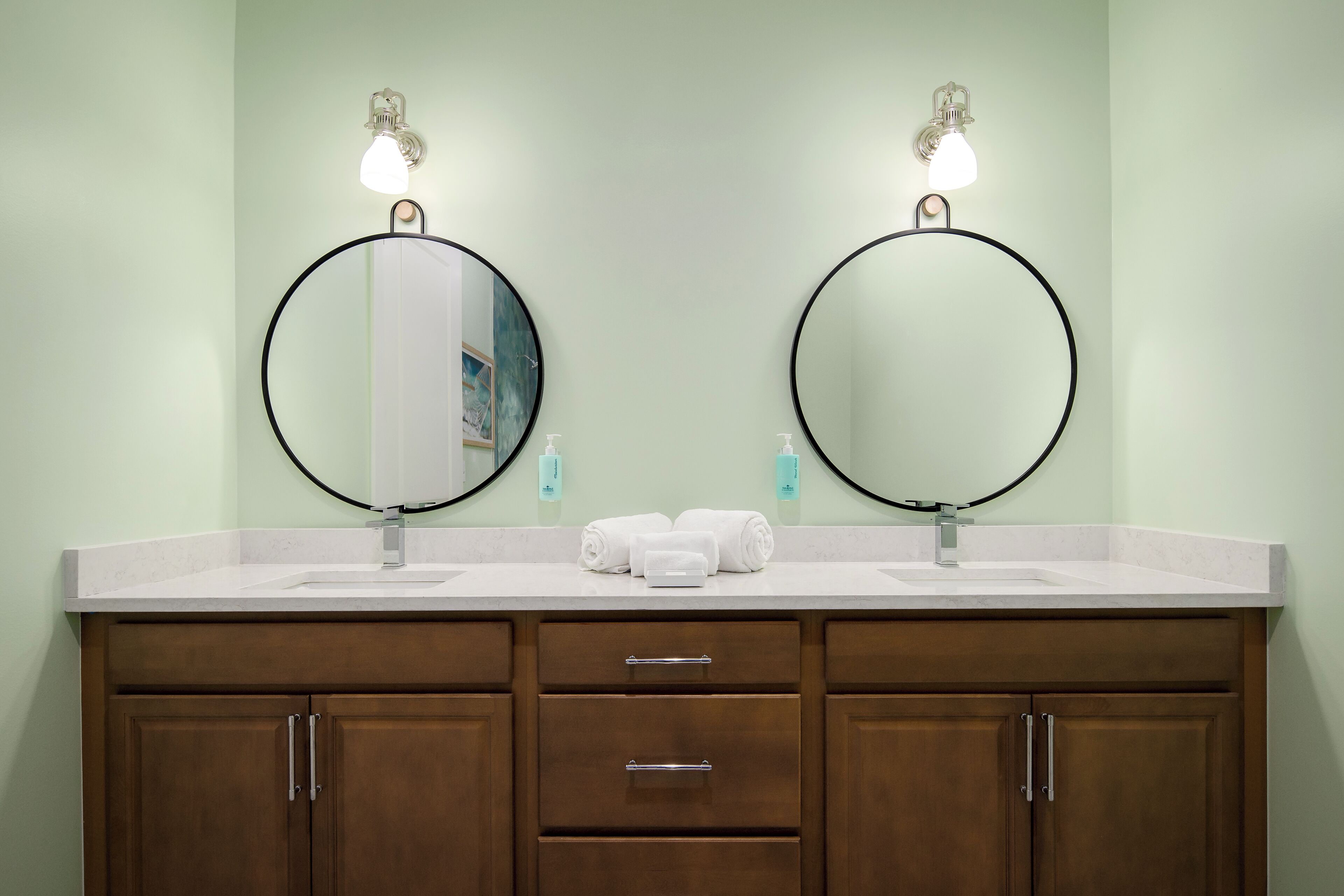 A bathroom with two sinks, a mirror, and a towel rack.