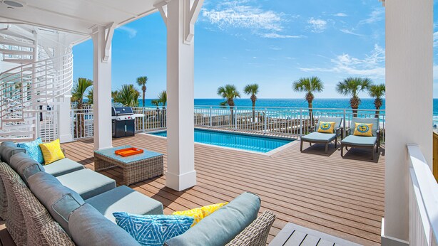 A covered outdoor deck with a pool, lounge chairs, and a view of the ocean. - Margaritaville Beach Cottage Resort PCB (Panama City Beach)