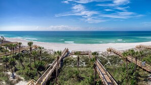 A beach with wooden boardwalks, palm trees, and a clear blue sky. - Margaritaville Beach Cottage Resort PCB (Panama City Beach)