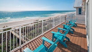 A wooden deck with blue chairs and a white railing overlooking a beach. - Margaritaville Beach Cottage Resort PCB (Panama City Beach)