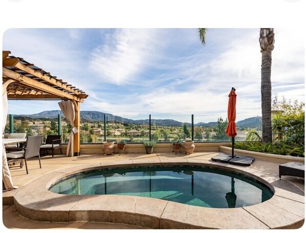 A pool area with a pergola, outdoor furniture, and a view of mountains.
