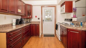 Une cuisine avec des meubles en bois, un four à micro-ondes, une cuisinière et une porte ornée de vitraux.