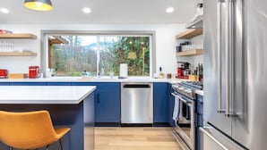 A modern kitchen with blue cabinets, a stainless steel refrigerator, and a dishwasher. - Waterfront Cabin at White Pass, Mt. Rainier (Packwood)