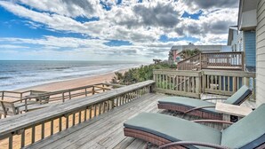 A wooden deck with wicker furniture overlooking a beach. - Beachfront Oasis w/ Game Room, Hot Tub & Ocean Views! (Flagler Beach)