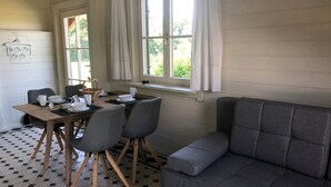 A dining area with a wooden table, four grey chairs, and a grey sofa. - Rotes Haus Füssen Apartment Klassik (Füssen)