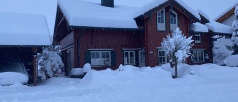 Ett tvåvåningshus byggt av tegel med ett snötäckt tak och ett garage.