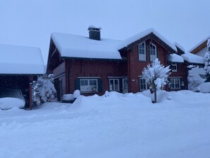 Ett tvåvåningshus byggt av tegel med ett snötäckt tak och ett garage.