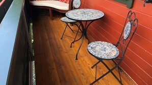 A wooden deck with a bench and two mosaic-topped tables, surrounded by red walls. - Rotes Haus Füssen Apartment Klassik (Füssen)