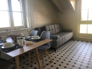 En matplats med ett bord dukat för två personer, en grå soffa och ett mönstrat golv.