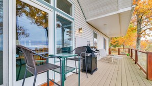 A covered outdoor area with a grill, chairs, and a table. - 17 Mi to Skiing! Lake-View Michigan Home w/ Deck (Harbor Springs)