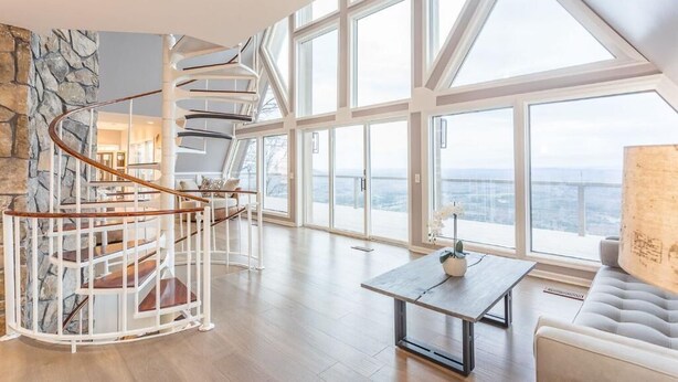 A spacious living area with a spiral staircase, large windows, and a view of the city.