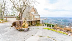 A house with a stone facade, large windows, and a balcony overlooking a scenic landscape.