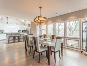 A modern kitchen with a dining area, large windows, and a chandelier.