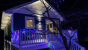 A two-story house with a balcony, decorated with multicolored string lights.