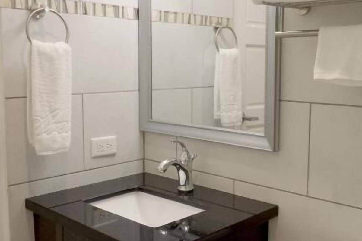 Une salle de bain avec un lavabo noir, des carreaux blancs, un miroir et des toilettes.