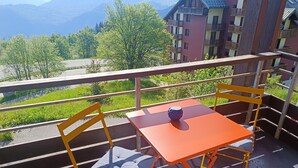 A balcony with yellow chairs and a table, overlooking a mountainous landscape and a road. - Le Corbier - Résidence Les Pistes, Appartement 6/7 Personnes au Pied des Pistes (Villarembert)