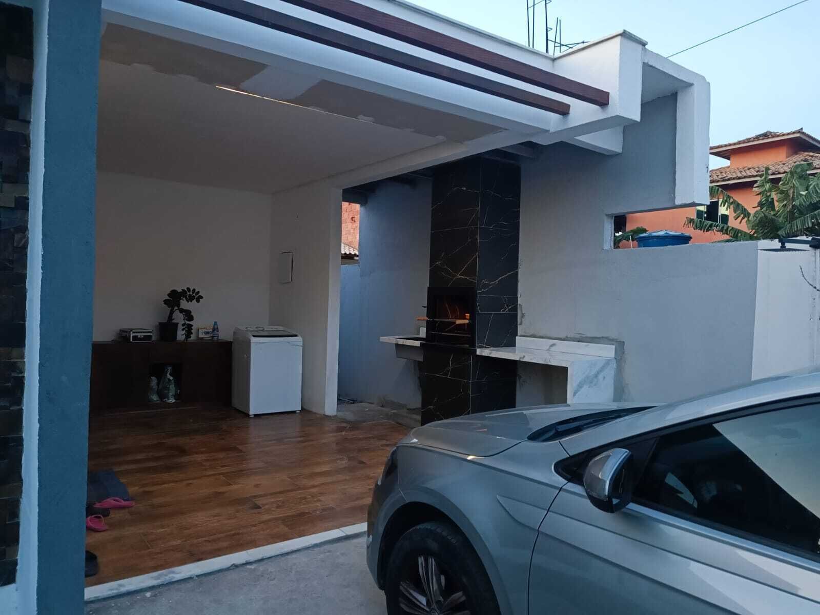 A modern house with a car parked in the driveway, a fireplace, and a small kitchen area.