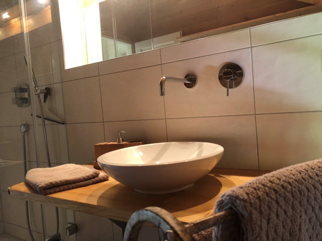 Ein Badezimmer mit einem großen, weißen Waschbecken, einem Spiegel und einem Handtuchhalter.