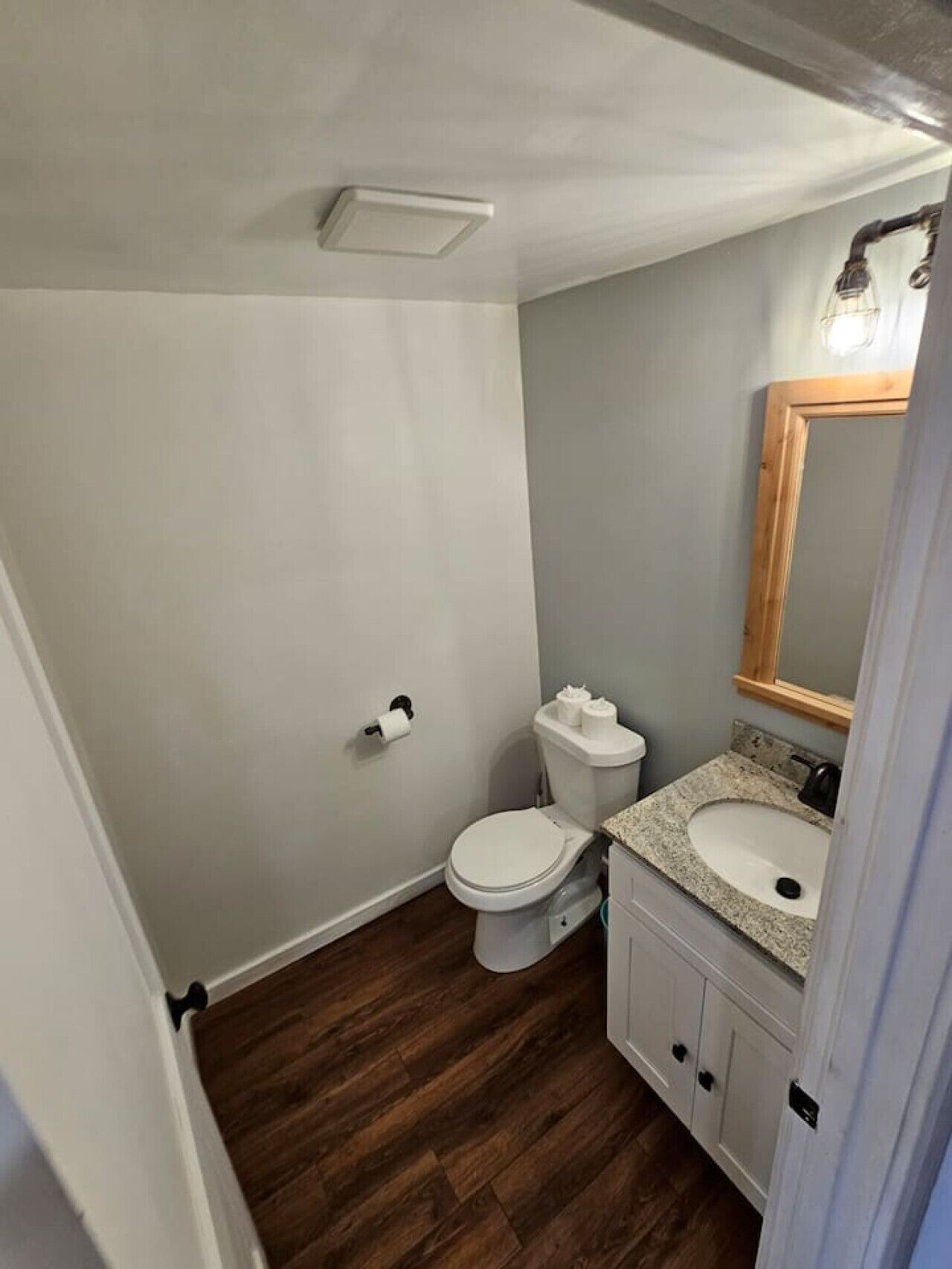 Un baño pequeño y funcional con inodoro, lavamanos y espejo.