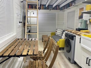 A compact kitchen with a washing machine, a dining table, and a bench.
