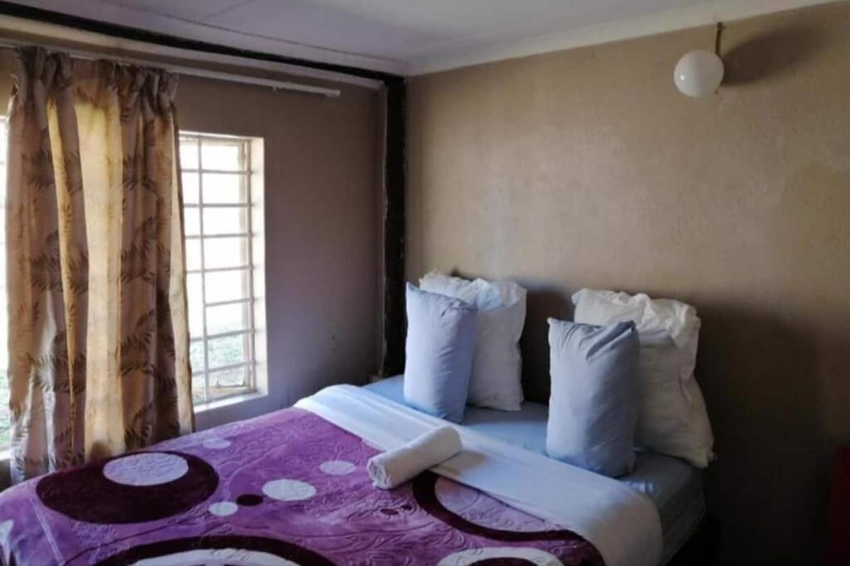 Ein Hotelzimmer mit Bett, Vorhängen, einem Fenster und einer Wandleuchte.