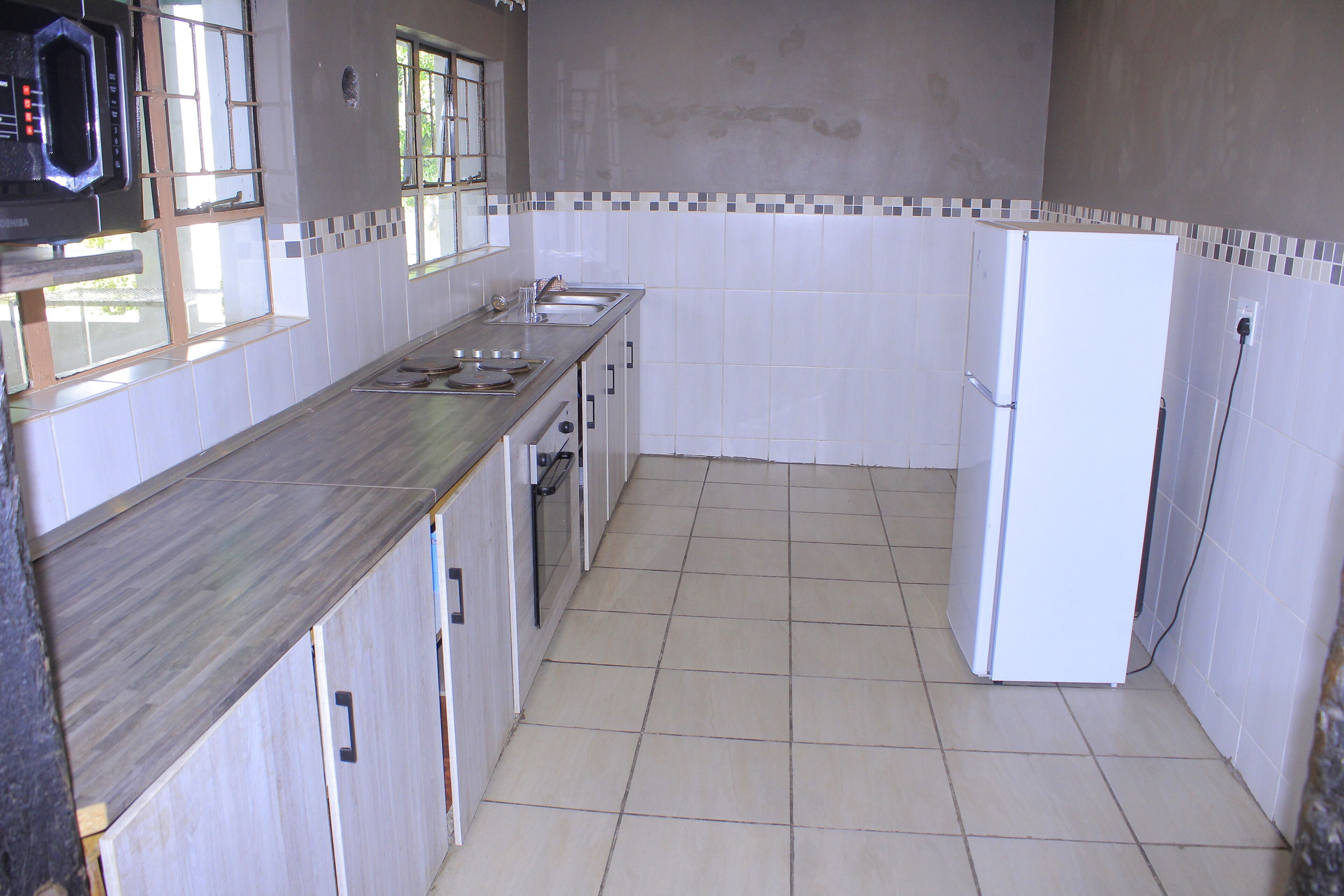 Una cocina con salpicadero de azulejos, un refrigerador y un microondas.