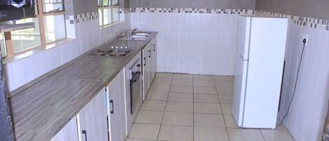 Una cocina con salpicadero de azulejos, un refrigerador y un microondas.