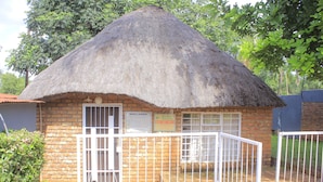 A small brick building with a thatched roof, a gated entrance, and a sign indicating Northern Security services. - Kaste guest house Tzaneen  (Tzaneen)