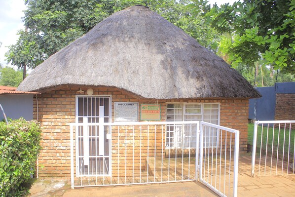A small brick building with a thatched roof, a gated entrance, and a sign indicating Northern Security services.