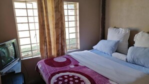 A bedroom with a bed, a television, and a window with curtains. - Kaste guest house Tzaneen  (Tzaneen)