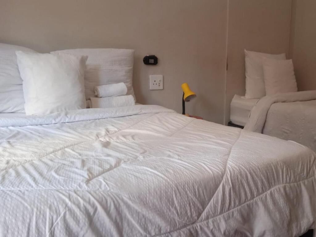A hotel room with a large bed, a bedside table, and a lamp.