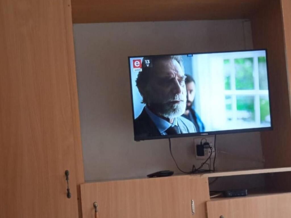 Un televisor montado en la pared con un mueble de madera debajo.