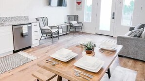 Une cuisine moderne avec un coin repas, un téléviseur fixé au mur et un ventilateur de plafond.