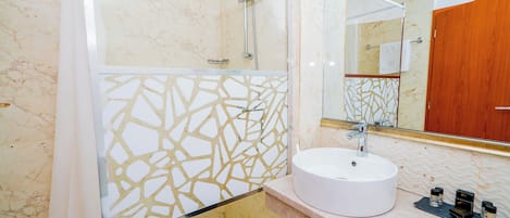 Un baño con lavamanos blanco, ducha y espejo.