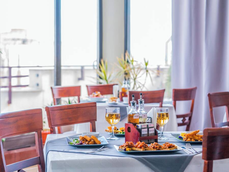 Une table à manger dressée avec des assiettes remplies de nourriture, des verres de vin et une bouteille d’huile d’olive.