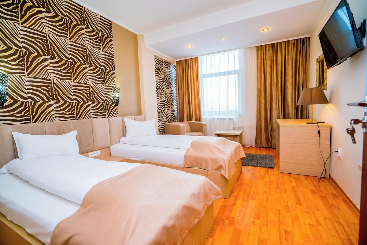 A hotel room with two beds, a sofa, a TV, and a wooden cabinet.