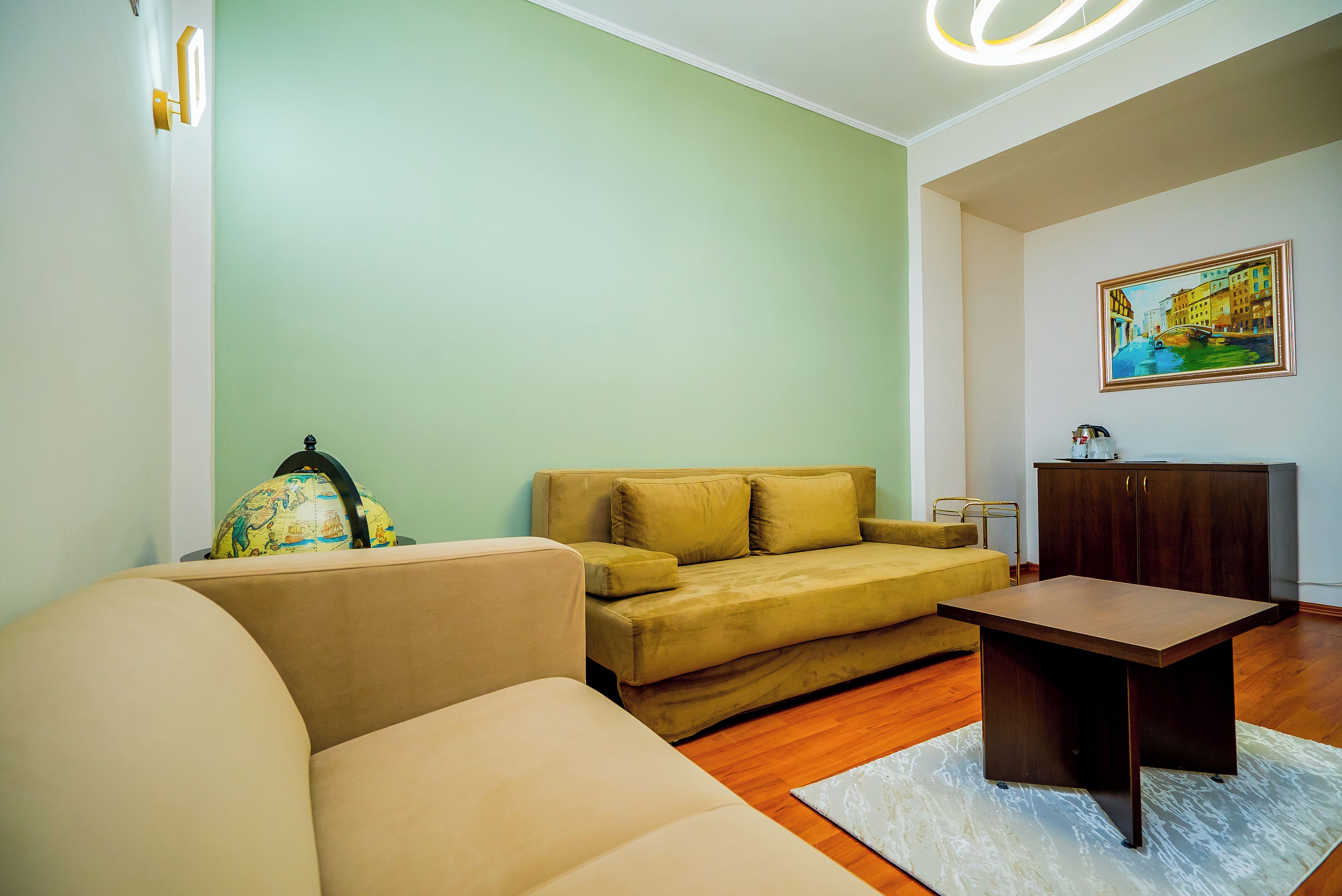 Una sala de estar con un sofá, una mesa de centro, un globo terráqueo y un cuadro en la pared.