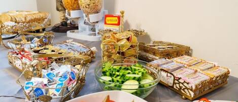 A buffet table with various food items, including bread, sandwiches, and a bowl of sliced cucumbers.