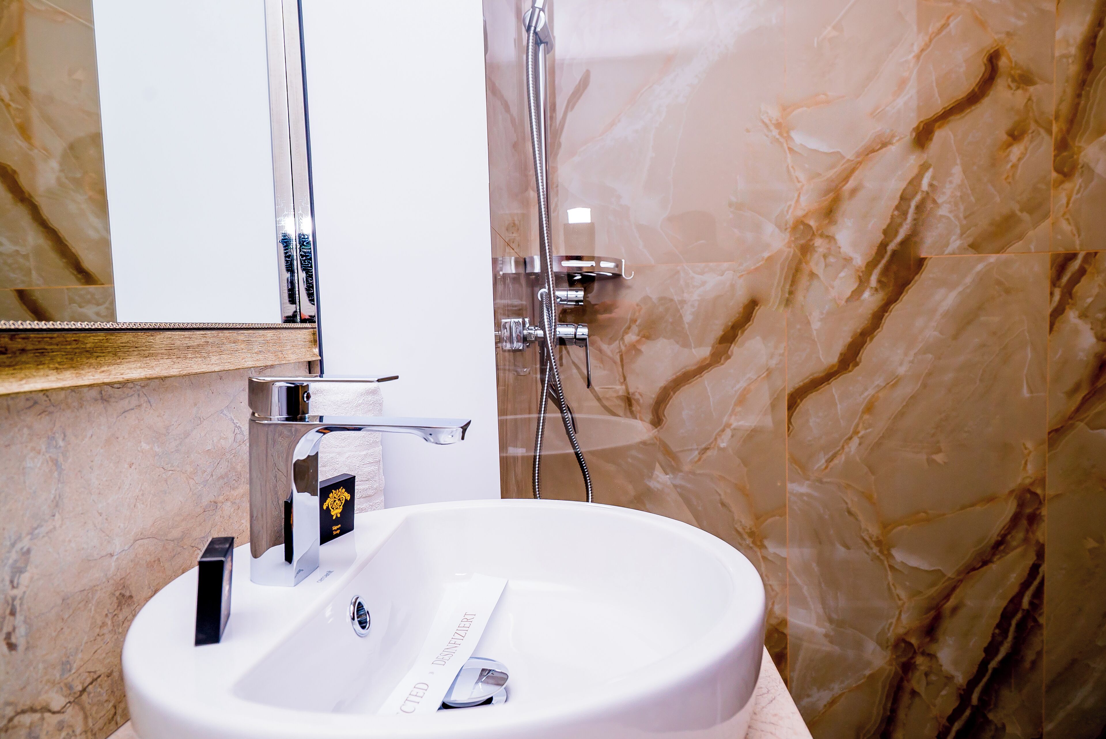 Een badkamer met een witte wastafel, een chromen kraan en een handdouche.
