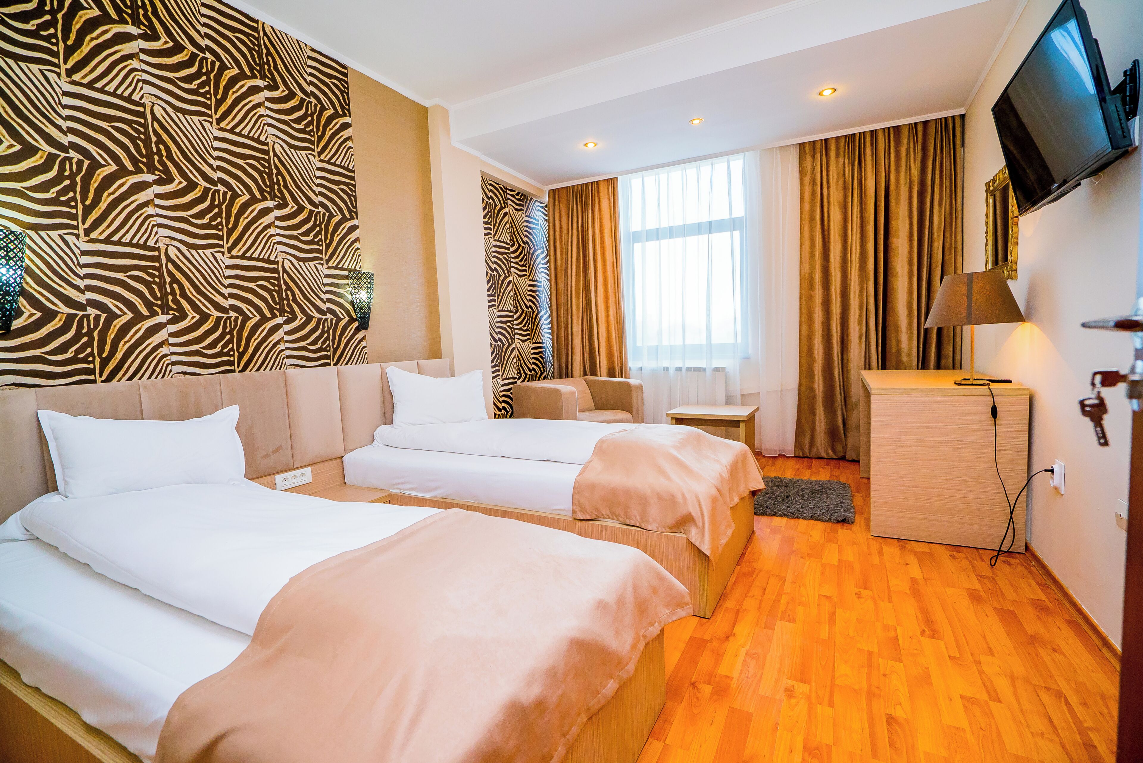 A hotel room with two beds, a sofa, a TV, and a wooden cabinet.