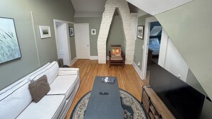 Ein Loft mit hohen Decken, einem weißen Ziegelbogen, einer Couch, einem Couchtisch und einem Fernseher.
