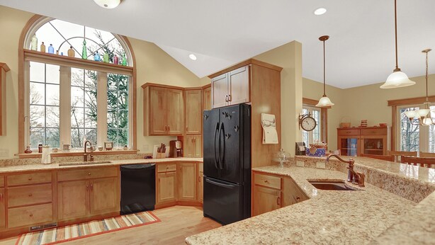 A spacious kitchen with wooden cabinets, a black refrigerator, granite countertops, and a large window with a view of trees. - Shamrock- Aunt Susie's- Raystown Lake- 7 Points (Hesston)