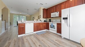 A spacious kitchen with wooden cabinets, a white refrigerator, and a built-in microwave.